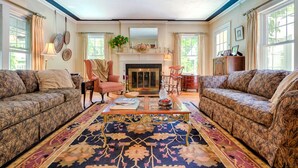 A spacious living room with two patterned sofas, a coffee table, and a fireplace. - Howarth House B&B (Fitchburg)