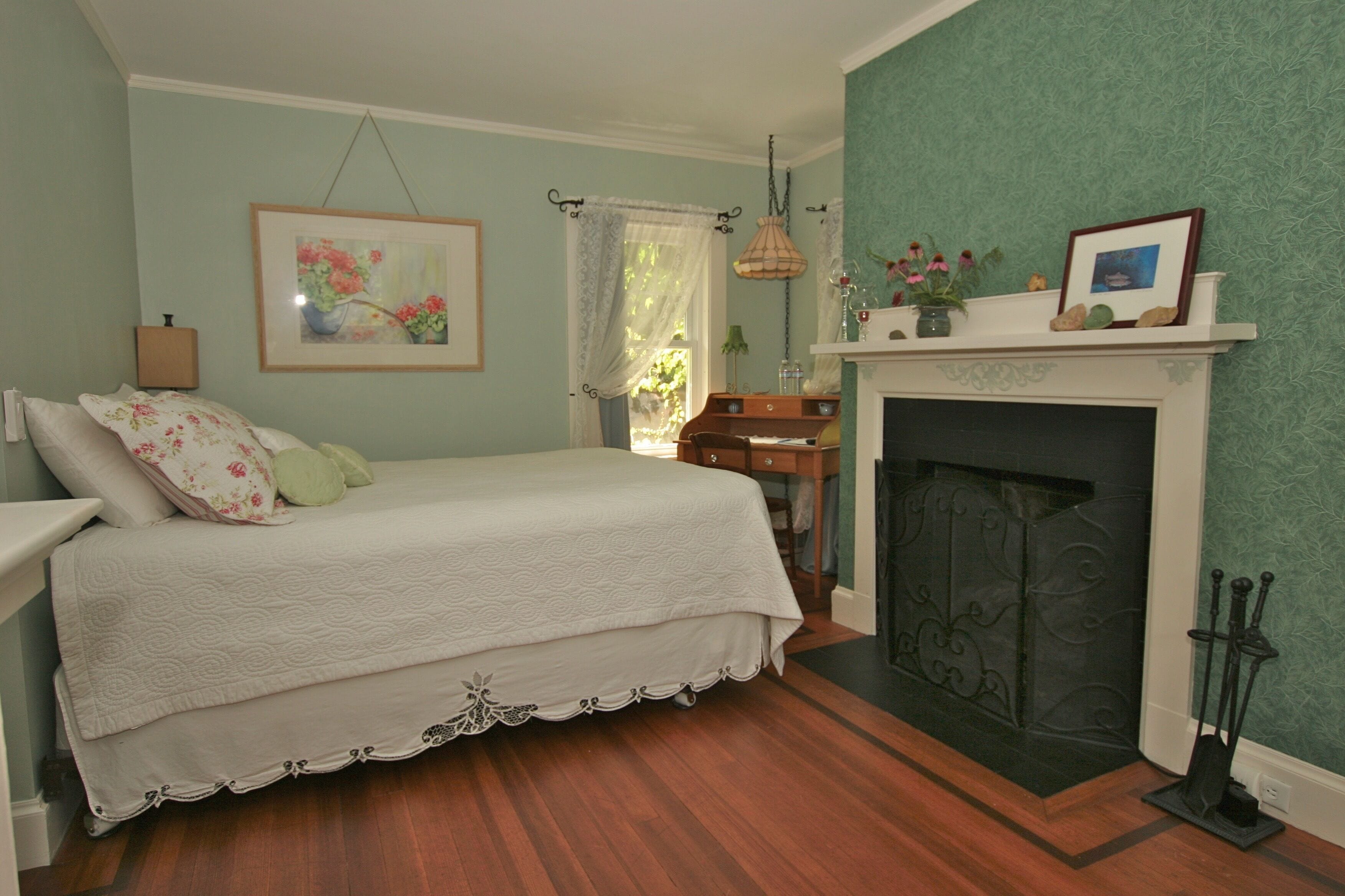 Une chambre à coucher avec un lit, une cheminée et un tableau au mur.