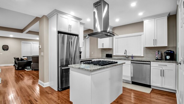 A modern kitchen with white cabinetry, stainless steel appliances, and a central island.