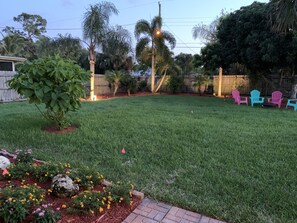Enjoy the serene atmosphere in this beautifully landscaped backyard with a lush lawn, trees, and a garden.