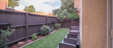A backyard with a wooden fence, a grassy lawn, and outdoor furniture.