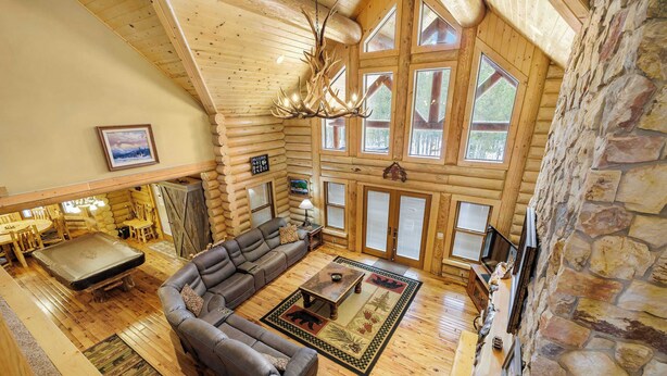 A log cabin interior with a sectional sofa, a fireplace, and a stone wall.