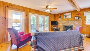 A cozy room with a bed, a chair, a television, and a fireplace. - Private Dock & Beach! Lake Norman Cottage Hideaway (Mooresville)