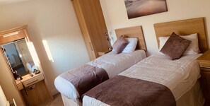 A hotel room with two beds, a wooden wardrobe, a mirror, and a painting on the wall. - The Armada Inn (Ballymoney)