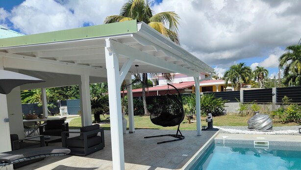 Un espacio exterior cubierto con piscina, asientos y una silla colgante.
