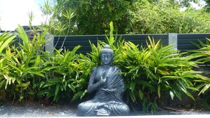 Una estatua de Buda en un jardín con una piscina al frente.