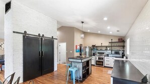 A modern kitchen with a central island, black appliances, and a white brick wall. - Stunning Large Getaway with HOT TUB (Flagstaff)