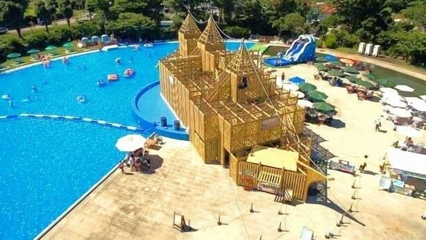 Ein großer Pool mit einer schlösserartigen Struktur in der Mitte, umgeben von Strandstühlen und Liegen.