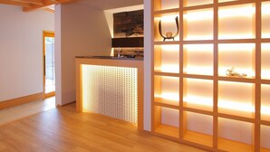 Ein modernes Interieur mit Holzboden, einer Trennwand mit beleuchteten Paneelen und einem kleinen Tisch mit einem dekorativen Gegenstand.