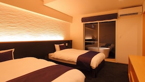 Ein Hotelzimmer mit zwei Betten, einem Badezimmer mit Badewanne und einem Schrank mit Schiebetür.