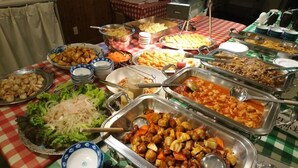 Une table de buffet proposant divers plats, notamment des salades, des viandes et des desserts.