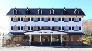 Un immeuble à plusieurs étages, doté d’une façade blanche et d’un toit foncé, portant l’inscription « HOLIDAY PLAZA ».