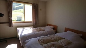 Une chambre avec deux lits, une fenêtre avec des rideaux et un radiateur.