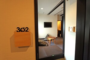A room with a sofa, a small table, and a TV mounted on the wall.