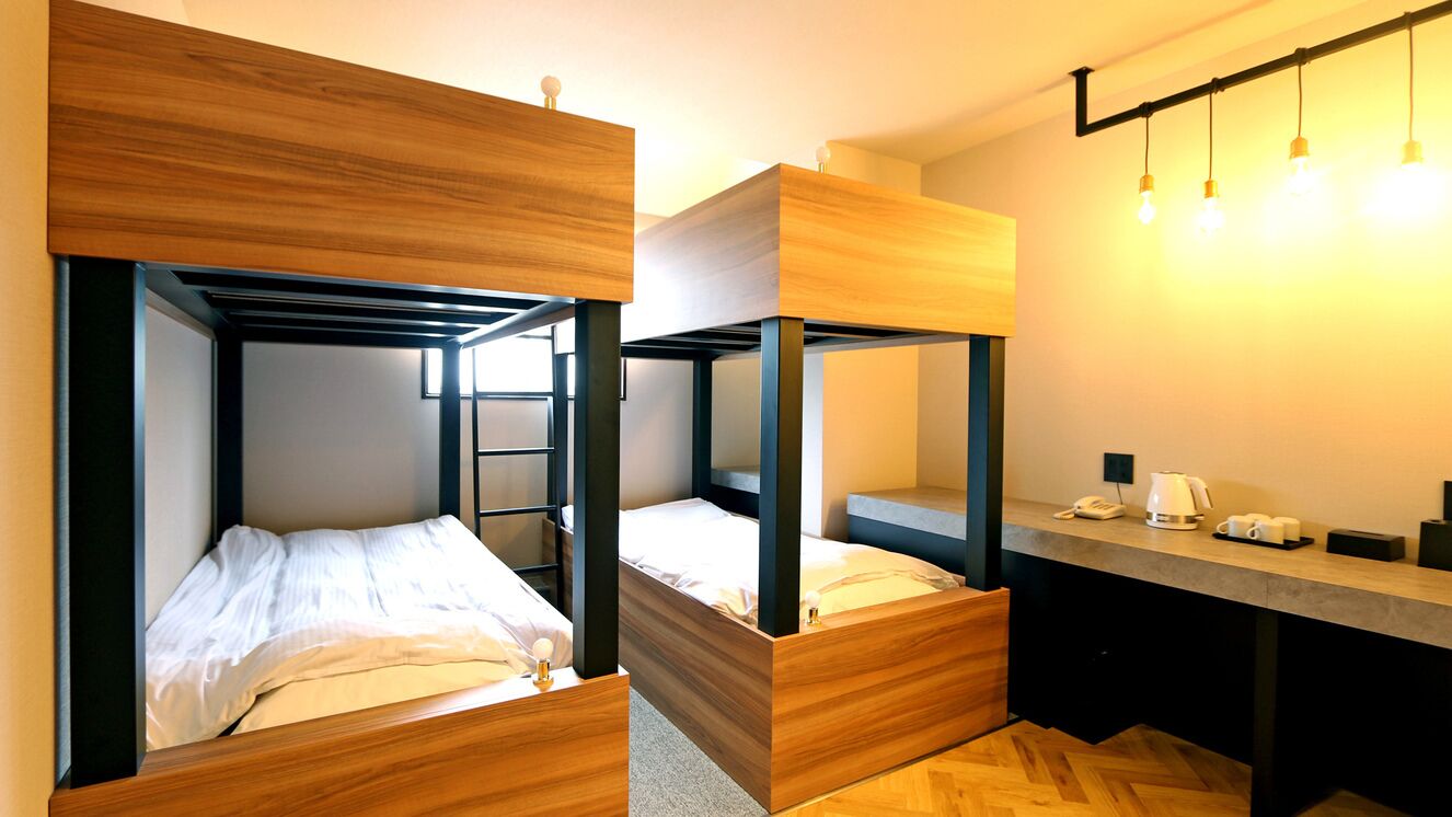 A modern hotel room with bunk beds, a desk, and a telephone.