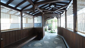 Un pasillo con vigas de madera, esteras de tatami y un sendero de piedra.