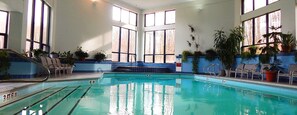 Swim laps in a spacious pool surrounded by large windows and lounge chairs.