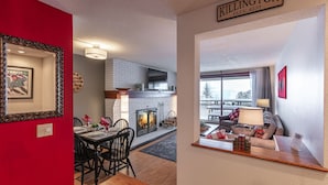 En moderne stue med pejs, et spiseområde med rød accentvæg og et køkken med murstensvæg.
