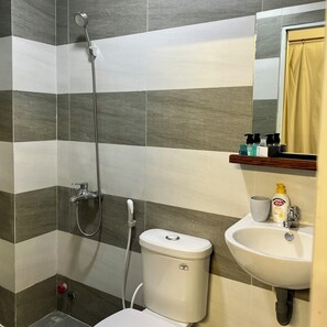 A bathroom with a shower, toilet, sink, and a mirror with a towel hanging. - Anh's House (Ho Chi Minh City)