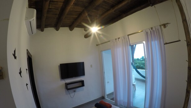 Un dormitorio con cama, televisor de pantalla plana en la pared y ventana con cortinas.