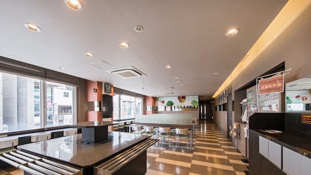 A modern restaurant interior with a central island, checkered floor, and large windows. - Super Hotel Matsumoto Ekimae (Matsumoto)