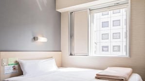A hotel room with a bed, a window, and a wall-mounted light. - Super Hotel Matsumoto Ekimae (Matsumoto)