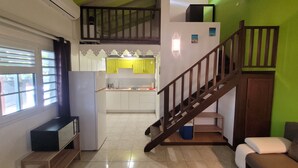 Un espacio habitable compacto con cocina, una escalera, un sofá y un televisor.