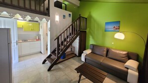 A living room with a brown leather sofa, a wooden coffee table, and a staircase leading to an upper level. - Eden Kay - 100m from the beach (Les Trois-Îlets)