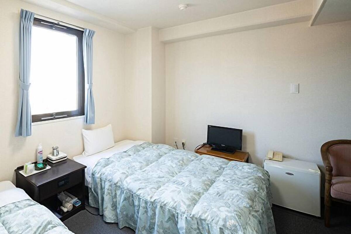 Een hotelkamer met twee bedden, een televisie, een stoel en een tafeltje met toiletartikelen.