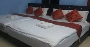 Un lit bien fait, avec des draps blancs, des coussins à motifs rouges et un plaid rouge.