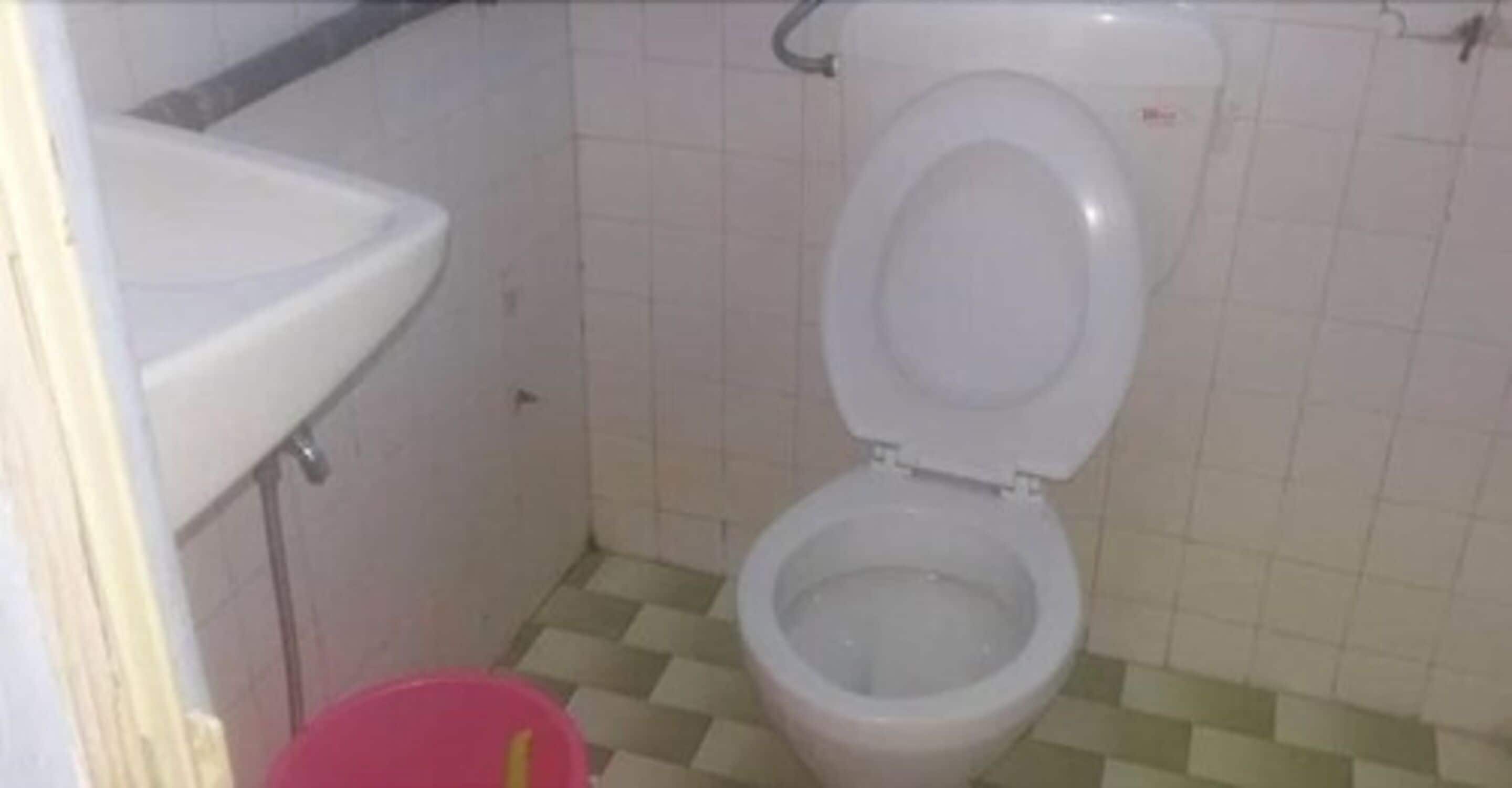 A small bathroom with a toilet, a sink, and a checkered floor.