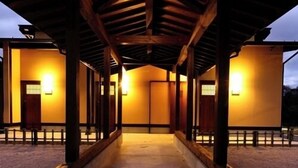 Un passage couvert mène à un bâtiment doté de plusieurs portes, chacune étant éclairée par un luminaire.