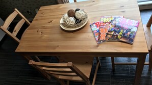 Een houten eettafel met tijdschriften en een gevlochten bal.