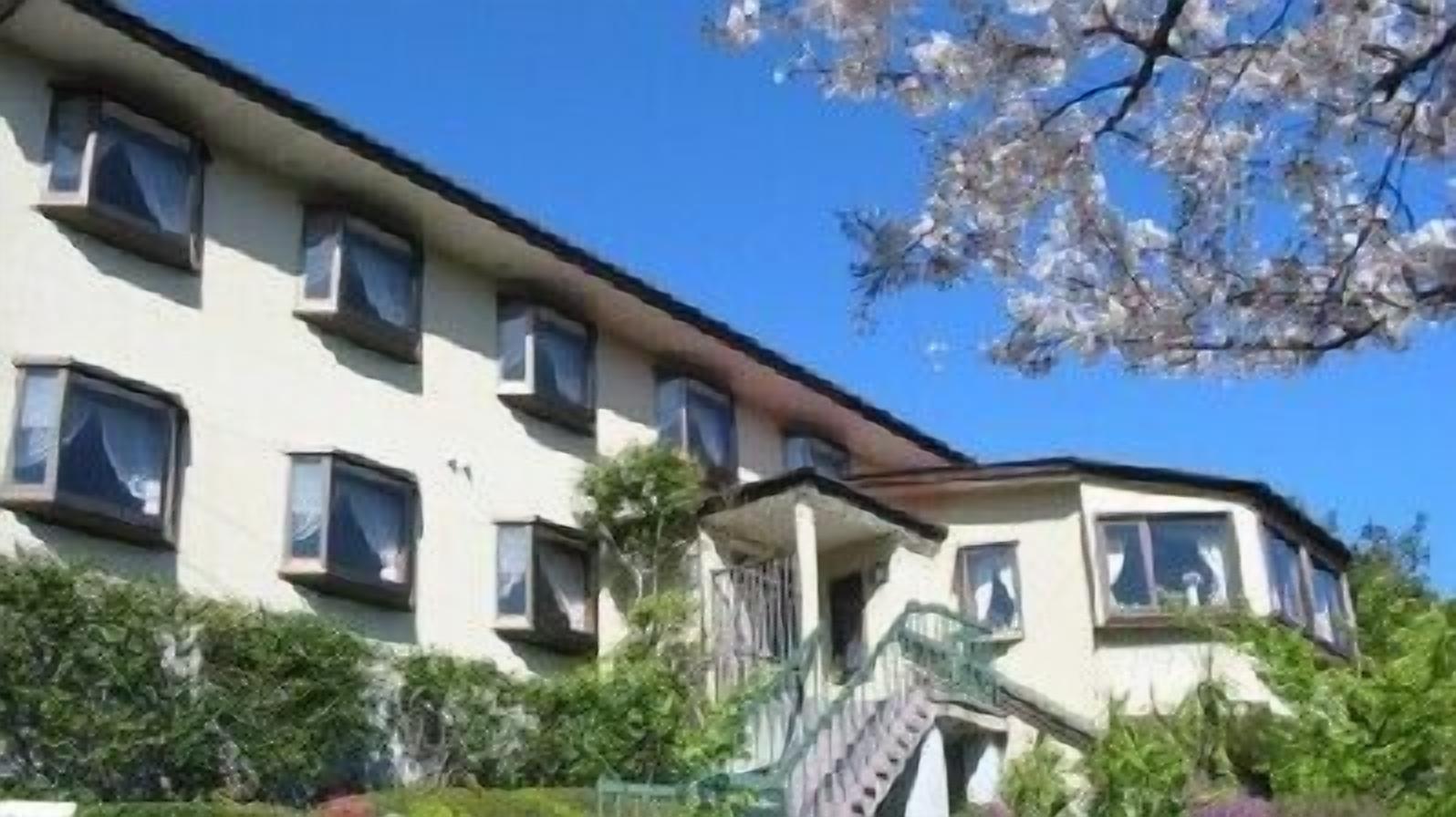 Un edifici de diverses plantes amb façana plana, nombroses finestres i una escala que condueix a l'entrada.