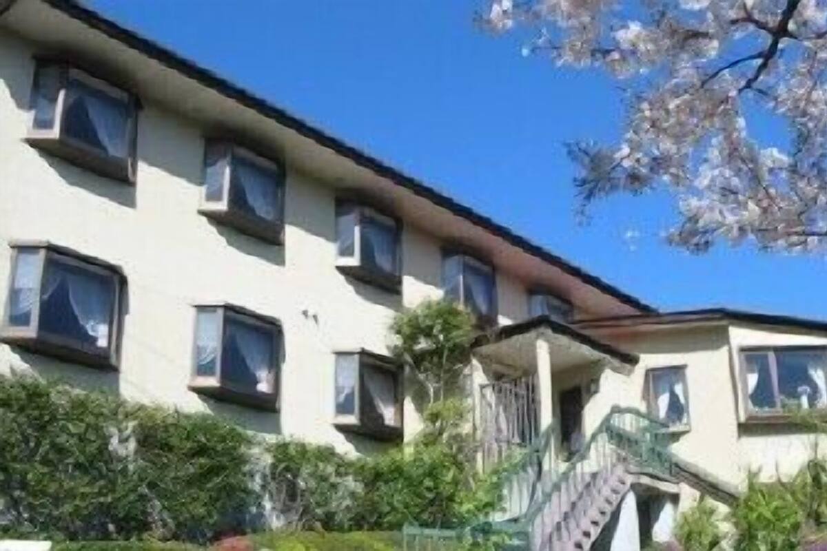 Un edificio de varios pisos con fachada plana, múltiples ventanas y una escalera que lleva a la entrada.