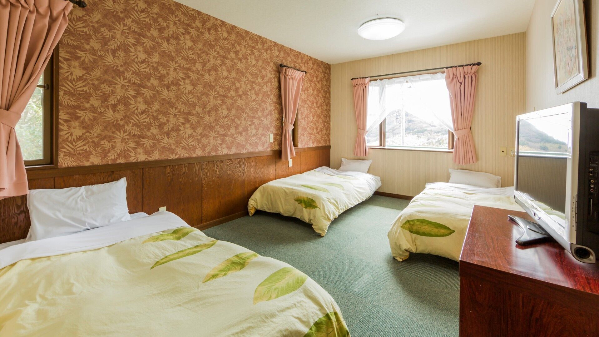 Habitació d'hotel amb dos llits, televisió i finestra amb cortines.