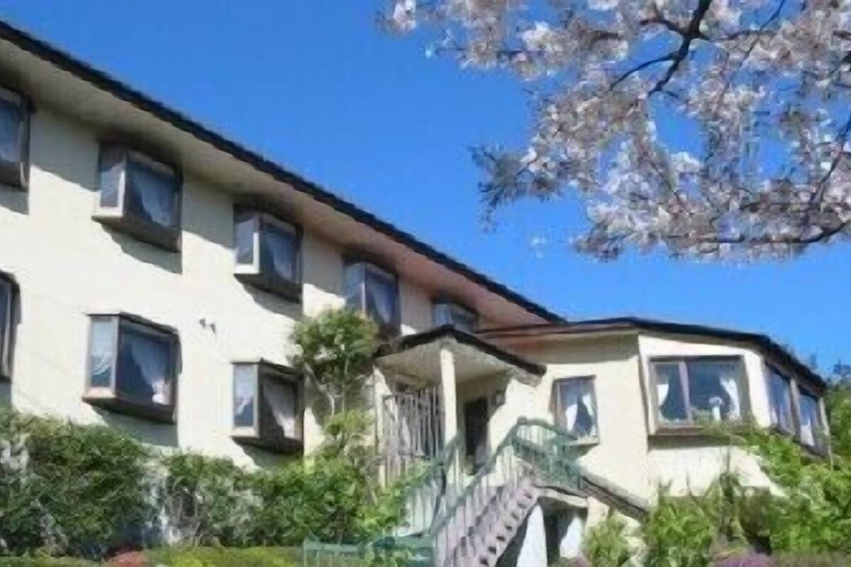 Un edificio de varios pisos con techo plano, múltiples ventanas y una escalera que conduce a la entrada.
