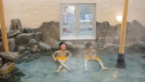 Een warmwaterbrongebied met stenen muren en een glazen deur.