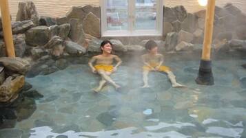 A hot spring area with stone walls and a glass door.