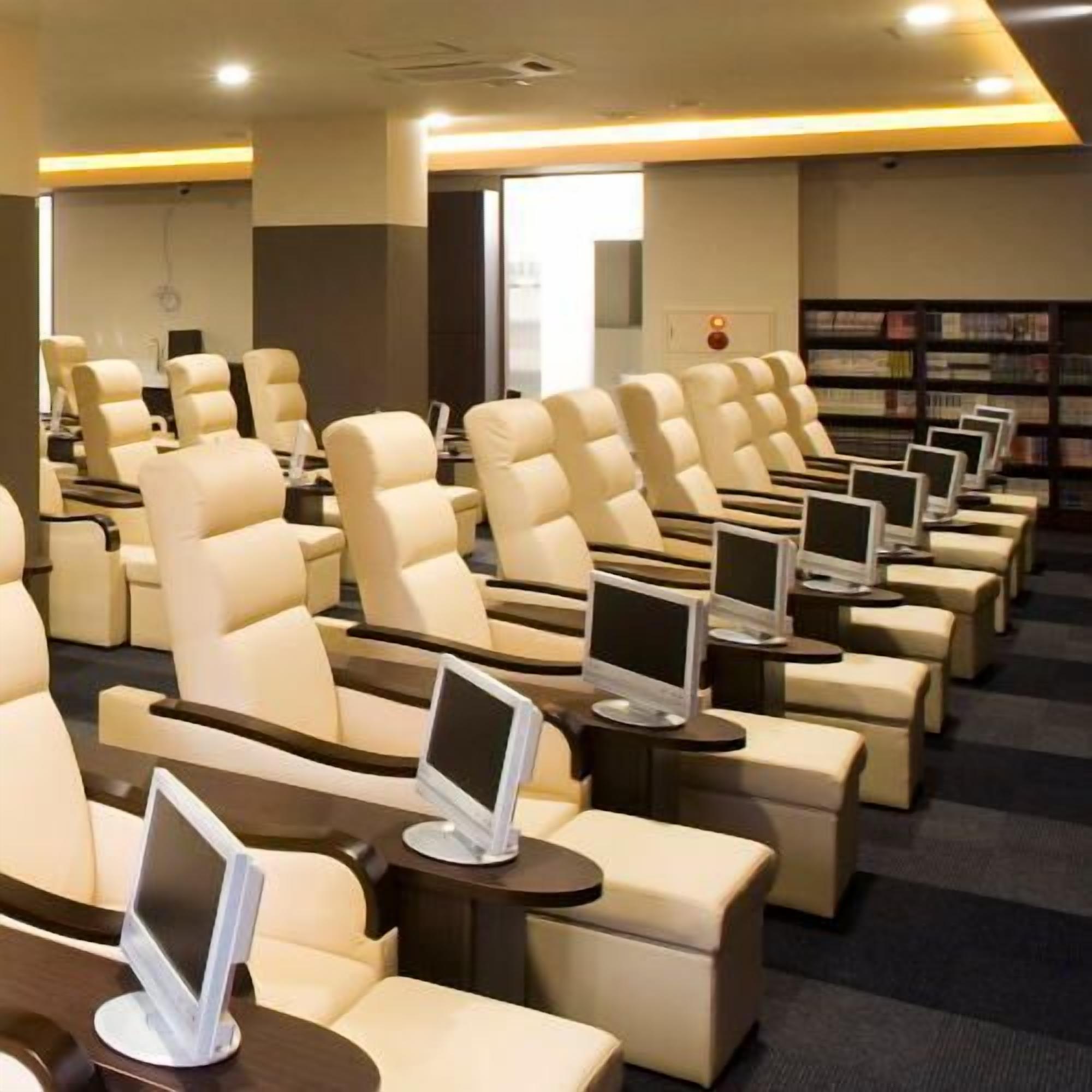 A row of reclining chairs with built-in screens, a bookshelf, and a modern interior design.