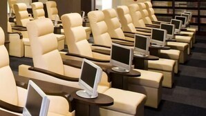 Een rij comfortabele fauteuils met geïntegreerde schermen, een boekenkast en een modern interieur.