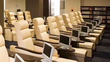 A row of reclining chairs with built-in screens, a bookshelf, and a modern interior design.
