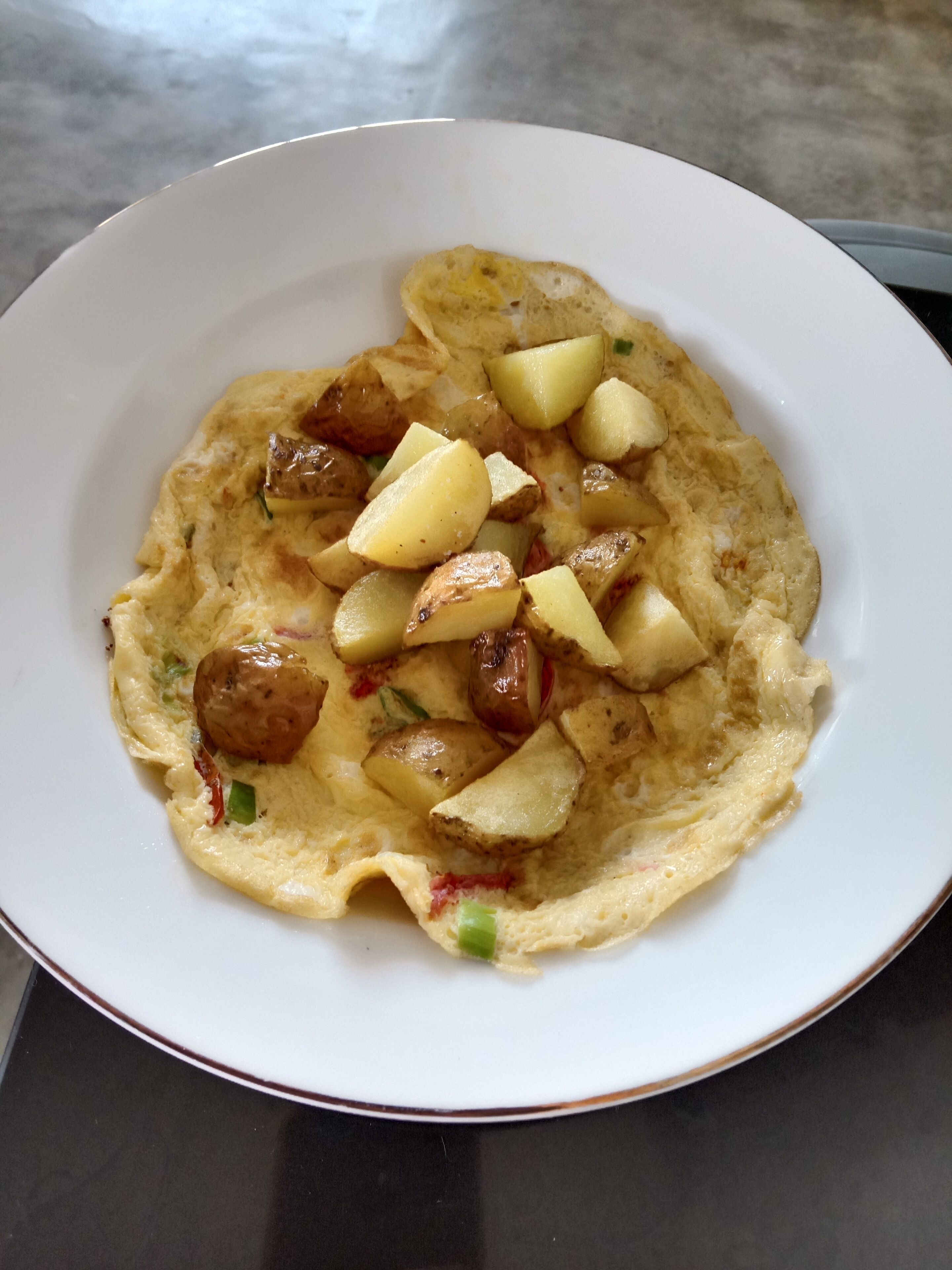 A plate of food with an omelette and diced potatoes.