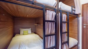 A bunk bed room with a wooden ceiling and a small shelf. - Fello Bnb Hostel Kuta - Adults Only (Kuta)