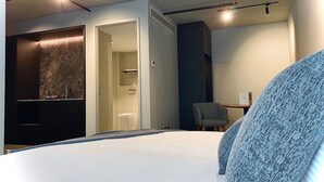 Une chambre d’hôtel avec un lit, un bureau, une chaise et une salle de bain.