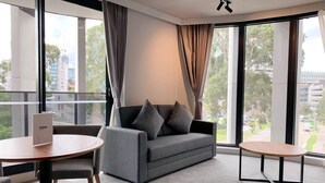 Une chambre d’hôtel moderne avec un canapé gris, une table ronde et une petite table ronde.