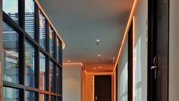 Un couloir moderne avec des murs en verre, un revêtement de sol en moquette et un éclairage encastré.