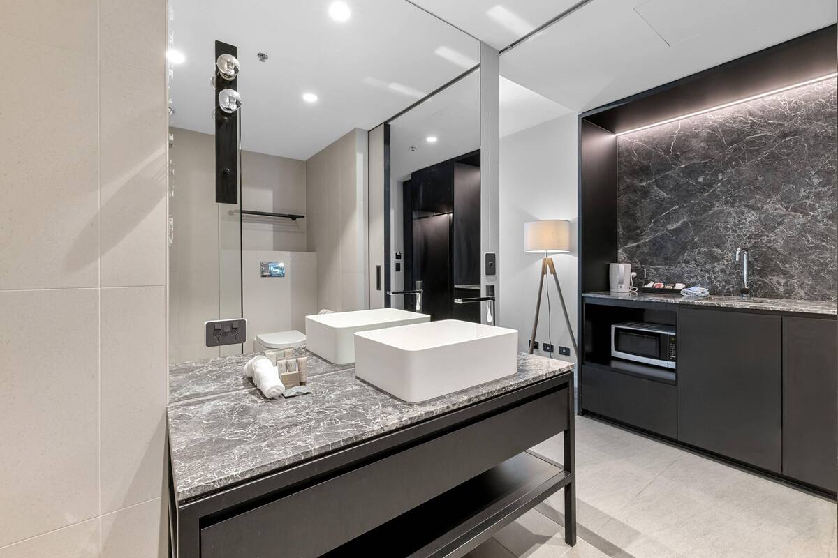 A modern bathroom with a double sink, a mirror, a vanity, and a marble backsplash.
