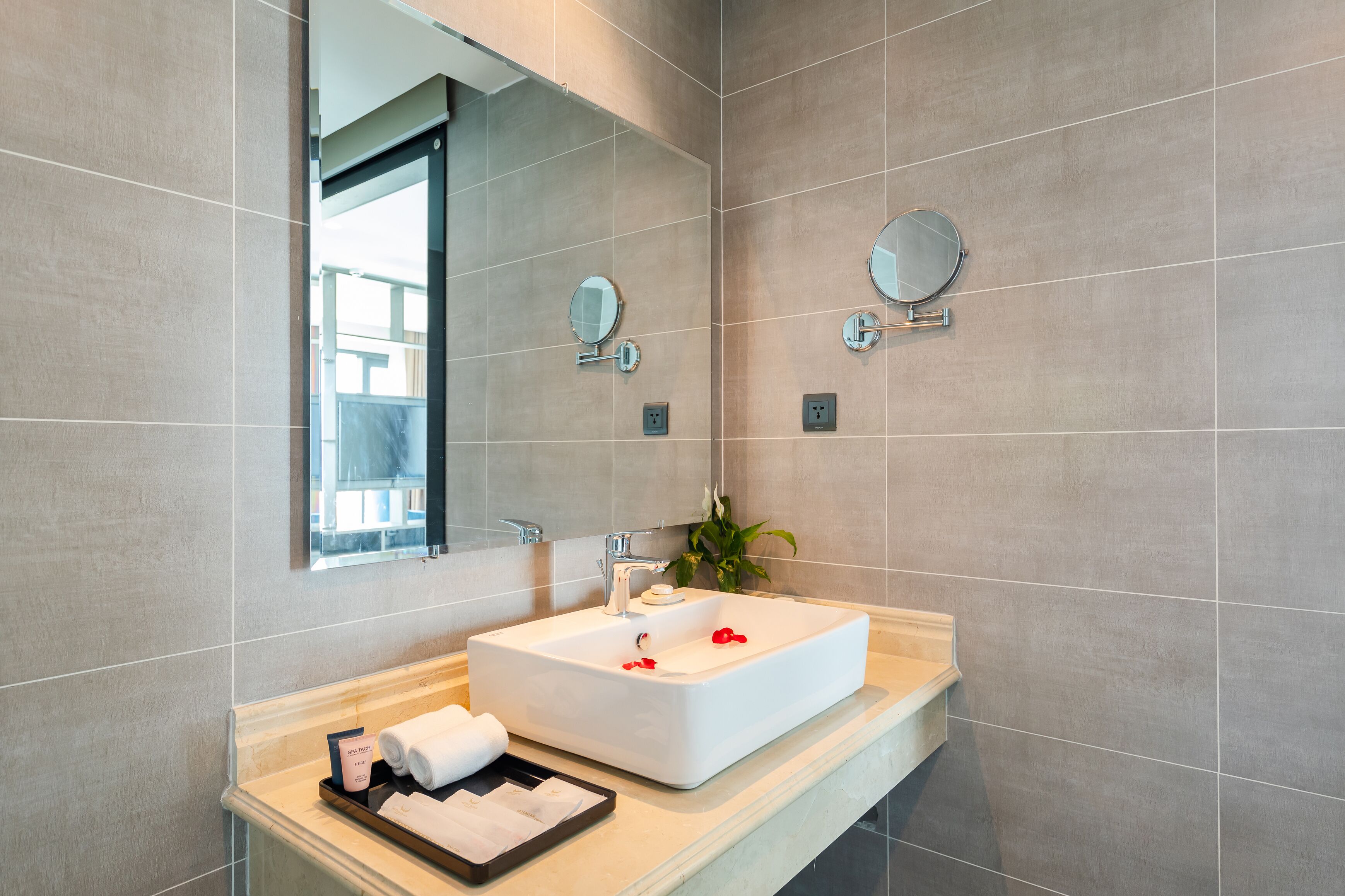 A modern bathroom with a rectangular sink, two wall-mounted mirrors, and a countertop with toiletries.