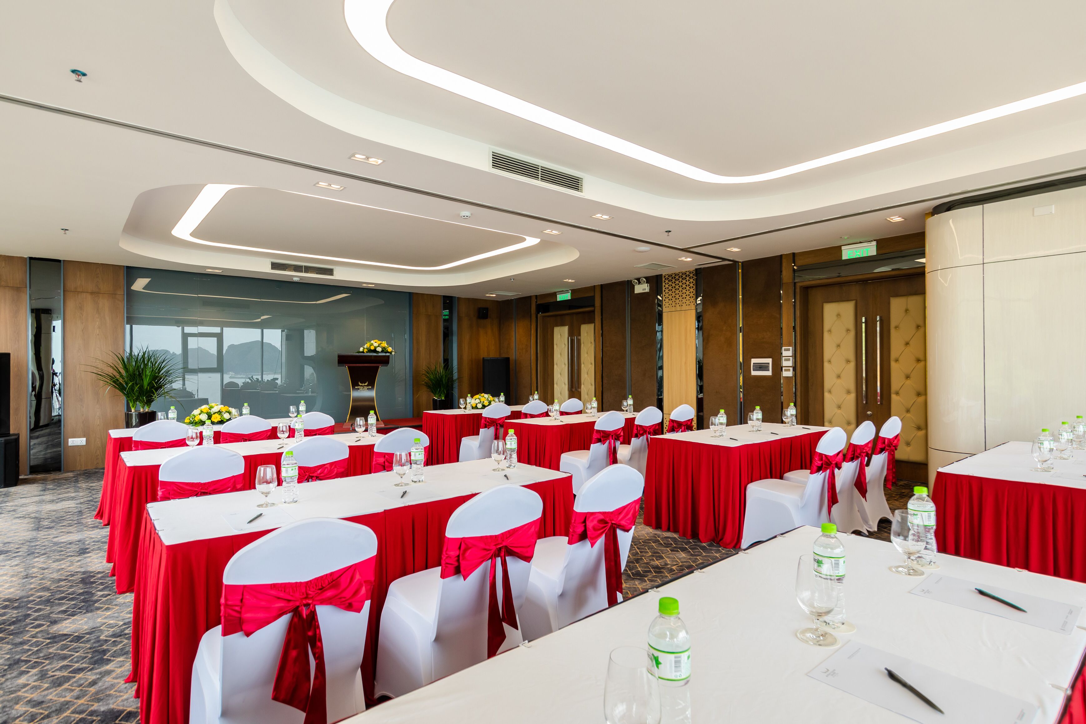 A conference room with tables set for a meeting, equipped with water bottles and notepads.